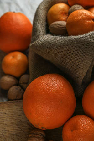 Ripe, tasty and juicy oranges, tangerines in a canvas bag with walnuts on the table.の写真素材