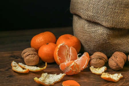Ripe, tasty and juicy oranges, tangerines in a canvas bag with walnuts on the table.の写真素材
