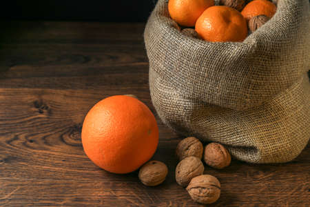 Ripe, tasty and juicy oranges, tangerines in a canvas bag with walnuts on the table.の写真素材