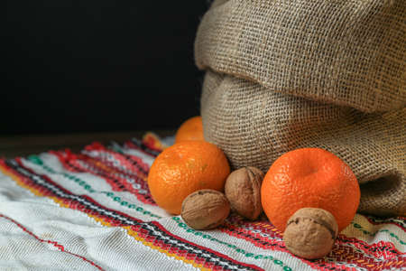 Ripe, tasty and juicy oranges, tangerines in a canvas bag with walnuts on the table.の写真素材