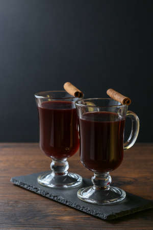 Mulled wine in glass cups with cinnamon and oranges on a wooden table.の写真素材