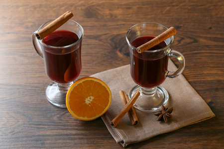 Mulled wine in glass cups with cinnamon and oranges on a wooden table.の写真素材