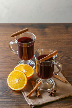 Mulled wine in glass cups with cinnamon and oranges on a wooden table.の写真素材