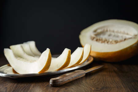 Whole and sliced melon, honey melon on wooden table background. Very healthy, natural, vegetarian food.の写真素材