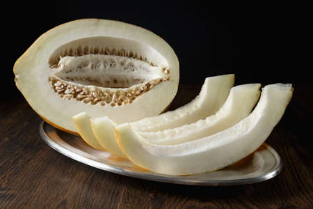 Whole and sliced melon, honey melon on wooden table background. Very healthy, natural, vegetarian food.の写真素材