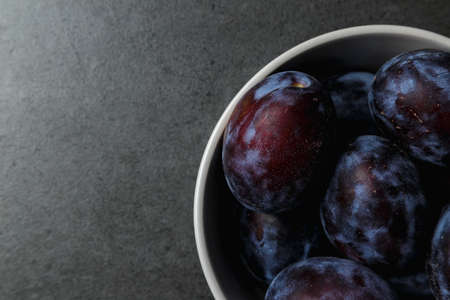 Blue plum in a bowl on a dark background. Top view. Place for text. Fruit background with copy space. Still life food.の写真素材