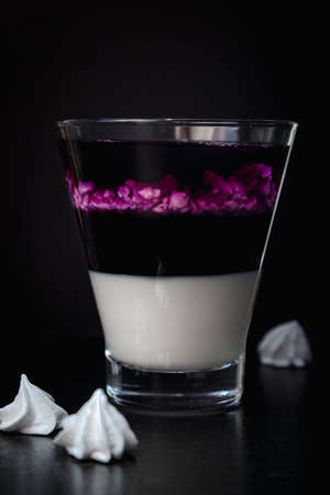 Blackberry panna cotta in glasses on a black background. Traditional Italian dessert with blackberry jelly and mint leaf.の写真素材