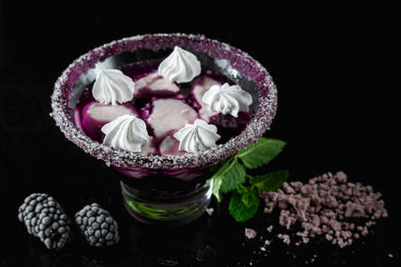Blackberry panna cotta in glasses on a black background. Traditional Italian dessert with blackberry jelly and mint leaf.の写真素材