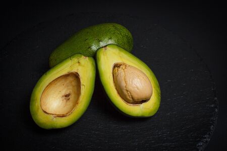 Sliced green avocado on a black beautiful surfaceの写真素材