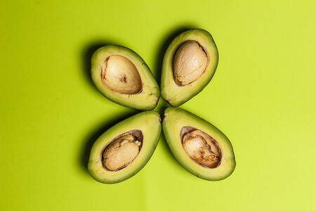 Sliced green colored avocado on a green background
