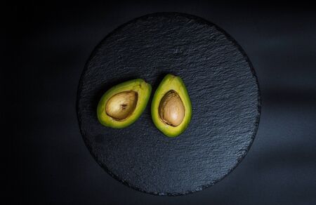 Sliced green avocado on a black beautiful surfaceの写真素材