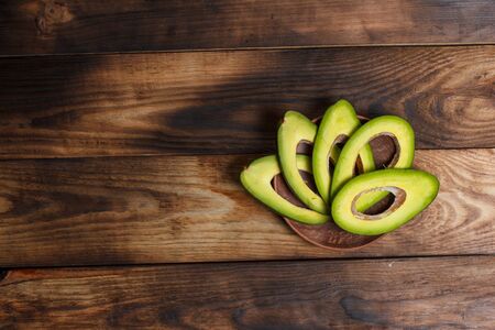 Sliced green avocado on a brown wooden table