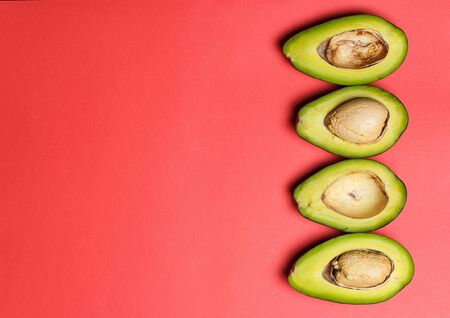 Sliced green avocado on a red beautiful surfaceの写真素材