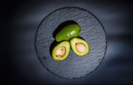 Sliced green avocado on a black beautiful surfaceの写真素材