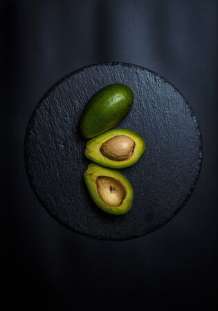 Sliced green avocado on a black beautiful surfaceの写真素材