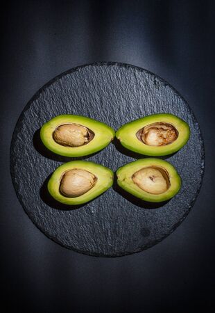 Sliced green avocado on a black beautiful surfaceの写真素材