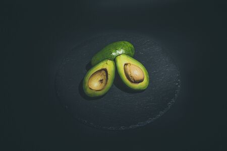 Sliced green avocado on a black beautiful surfaceの写真素材