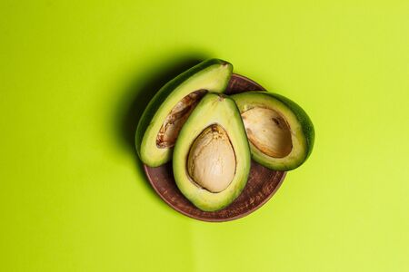 Sliced green colored avocado on a green backgroundの写真素材