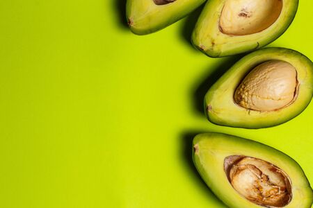 Sliced green colored avocado on a green backgroundの写真素材