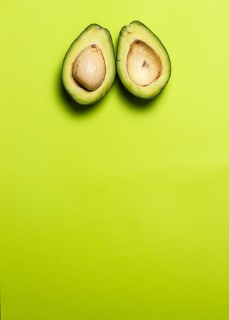 Sliced green colored avocado on a green backgroundの写真素材