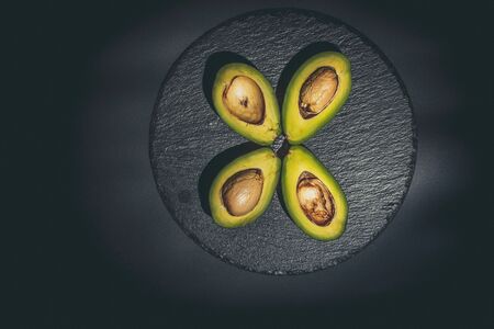 Sliced green avocado on a black beautiful surfaceの写真素材
