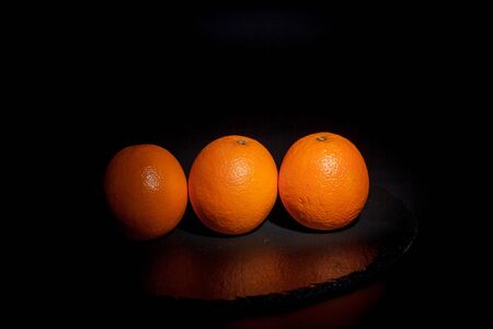 Sweet ripe orange on a black surface and black backgroundの写真素材