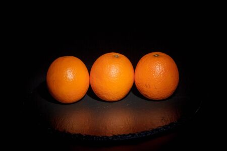 Sweet ripe orange on a black surface and black backgroundの写真素材