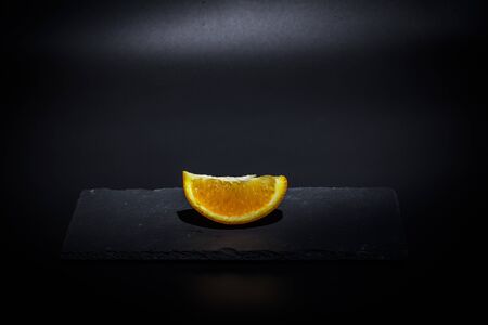 Sweet ripe orange on a black surface and black backgroundの写真素材