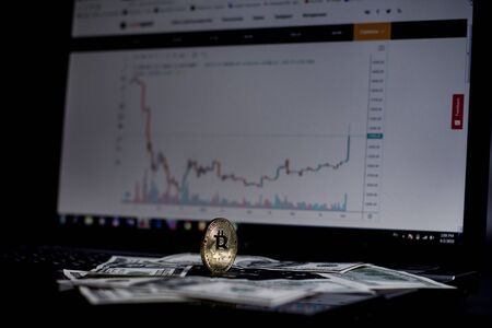 Golden bitcoin and dollars on laptop keyboardの写真素材