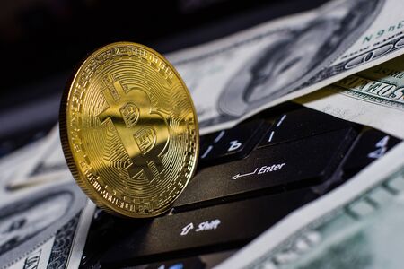 Golden bitcoin and dollars on laptop keyboardの写真素材
