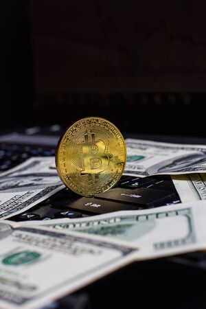 Golden bitcoin and dollars on laptop keyboardの写真素材