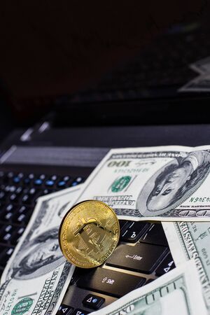 Golden bitcoin and dollars on laptop keyboardの写真素材
