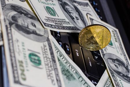 Golden bitcoin and dollars on laptop keyboardの写真素材
