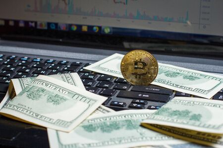 Golden bitcoin and dollars on laptop keyboardの写真素材