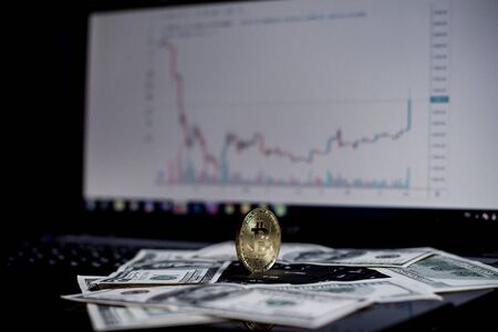Golden bitcoin and dollars on laptop keyboardの写真素材