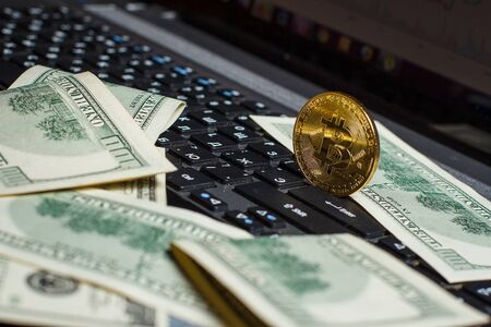Golden bitcoin and dollars on laptop keyboardの写真素材