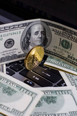 Golden bitcoin and dollars on laptop keyboardの写真素材