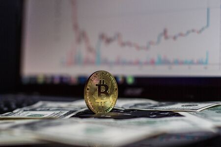 Golden bitcoin and dollars on laptop keyboardの写真素材