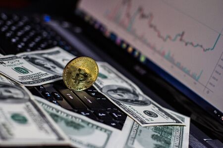 Golden bitcoin and dollars on laptop keyboardの写真素材