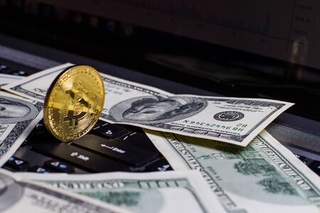 Golden bitcoin and dollars on laptop keyboardの写真素材