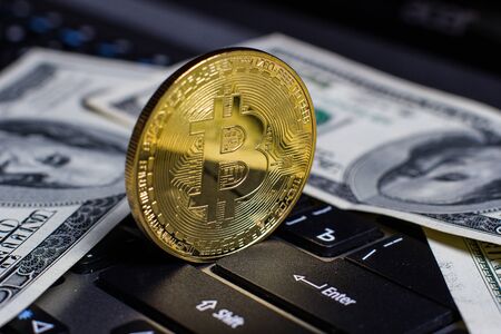 Golden bitcoin and dollars on laptop keyboardの写真素材