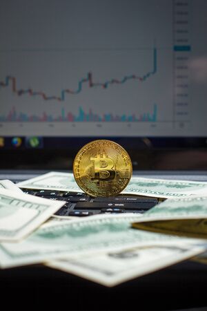 Golden bitcoin and dollars on laptop keyboardの写真素材