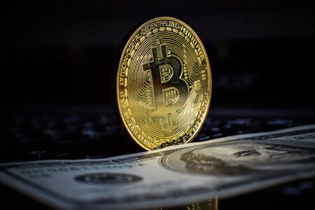 Golden bitcoin and dollars on laptop keyboardの写真素材
