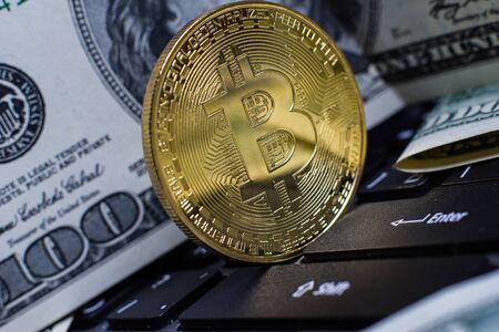 Golden bitcoin and dollars on laptop keyboardの写真素材