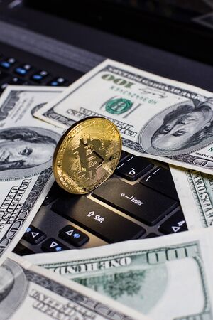 Golden bitcoin and dollars on laptop keyboardの写真素材
