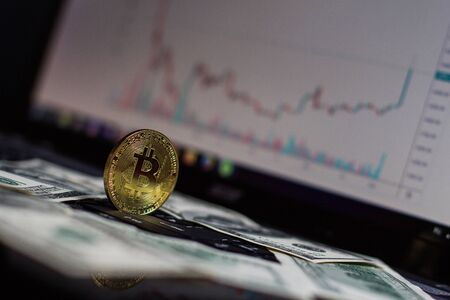 Golden bitcoin and dollars on laptop keyboardの写真素材