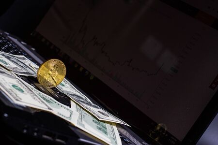 Golden bitcoin and money on laptop keyboardの写真素材