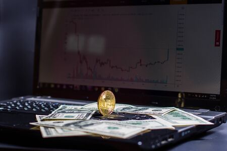 Golden bitcoin and money on laptop keyboardの写真素材