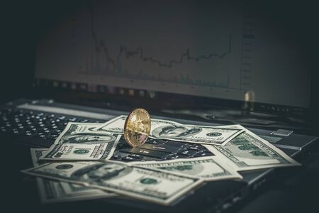 Golden bitcoin and money on laptop keyboardの写真素材