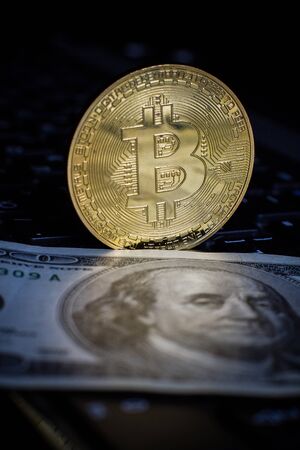 Golden bitcoin and money on laptop keyboard